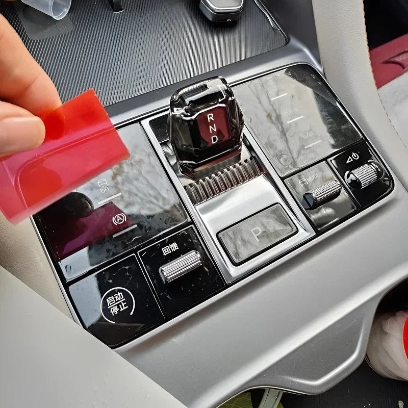 Red translucent protective film being applied to a black BYD car gear shifter console.