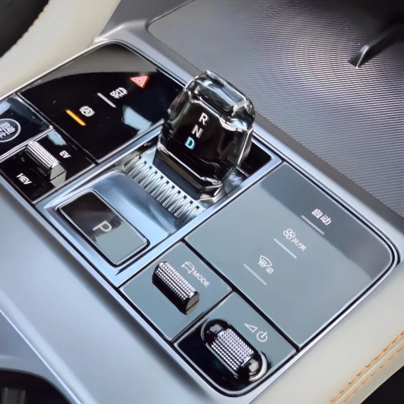 Glossy black crystal gear shifter with RND indicator and silver metallic control knobs.