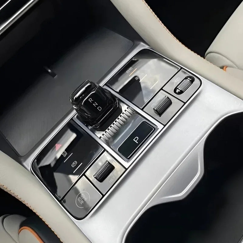 Black electronic gear shifter and silver metallic center console control panel in a car interior.
