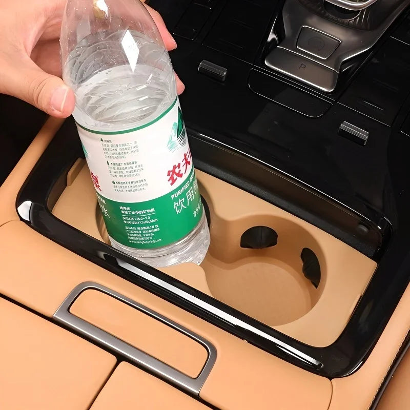 A clear plastic water bottle placed in a tan-colored car cup holder with a black rim.