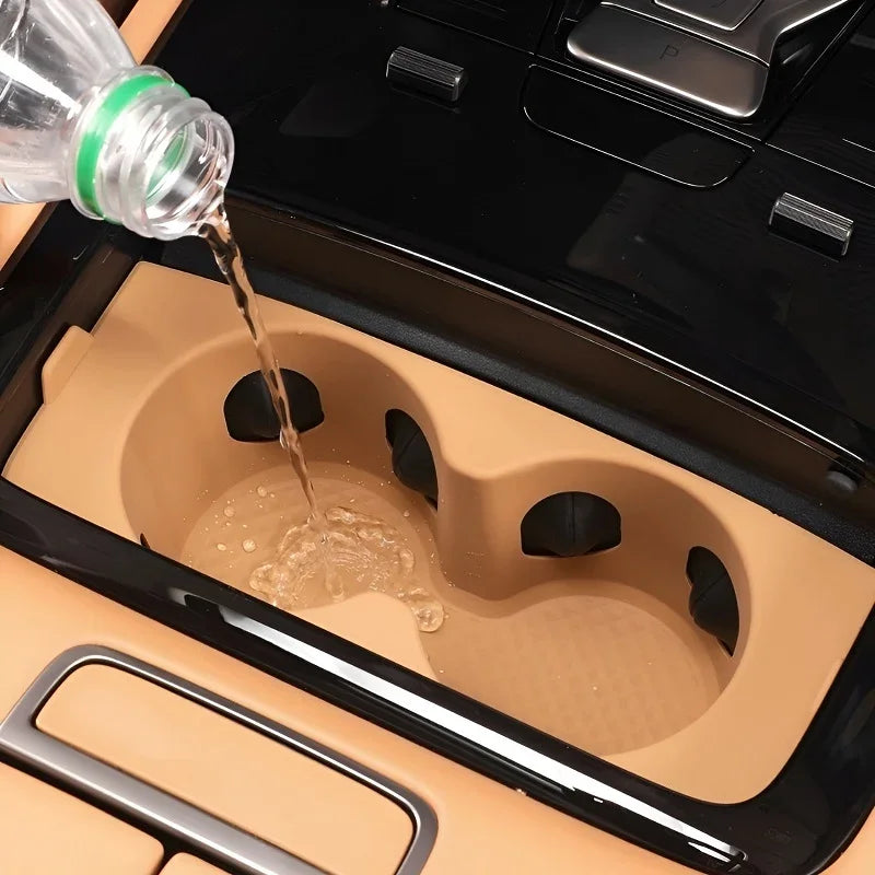 Water being poured into a tan silicone car cup holder liner to demonstrate spill protection.