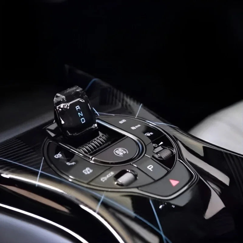Glossy black carbon fiber texture center console with illuminated gear shifter and control buttons.