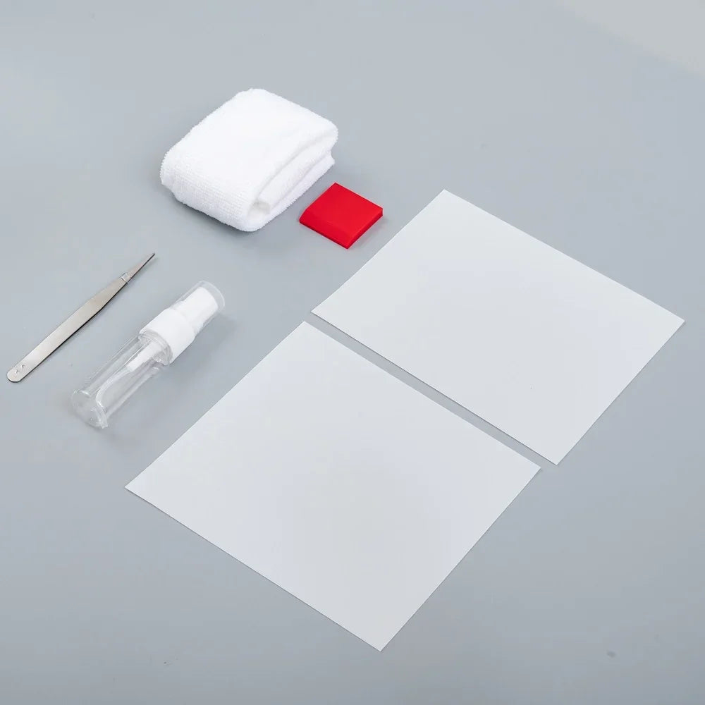 Cleaning kit with white microfiber cloth, red eraser, spray bottle, tweezers, and white sheets.