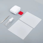 Cleaning kit with white microfiber cloth, red eraser, spray bottle, tweezers, and white sheets.