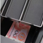 Black textured anti-slip car floor mat protecting a 100 Yuan banknote in a storage compartment.