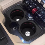 Dual black matte cup holders with silver metallic accents in a beige car interior.