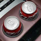 Two red aluminum beverage cans secured in premium brown leather car center console cup holders.