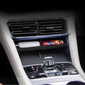 Black leather car center console organizer tray holding a white USB drive and colorful accessory.