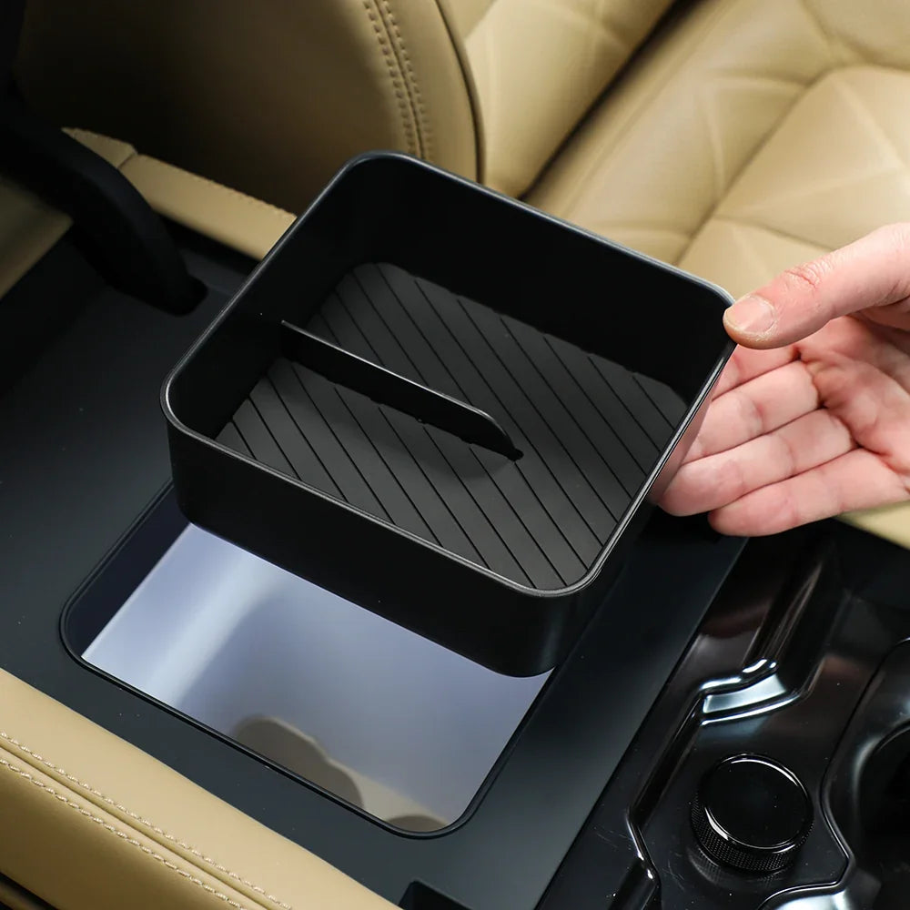 Black matte plastic car center console organizer tray being placed into a vehicle interior.