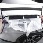 Clear protective film with black trim being applied to a white car's rear bumper.