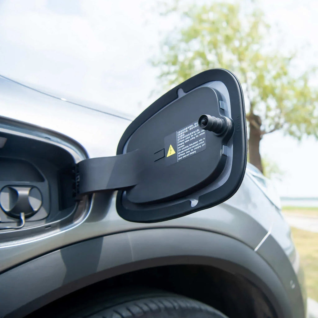 Open black protective charging port cover on a silver BYD electric vehicle.