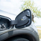 Open black protective charging port cover on a silver BYD electric vehicle.