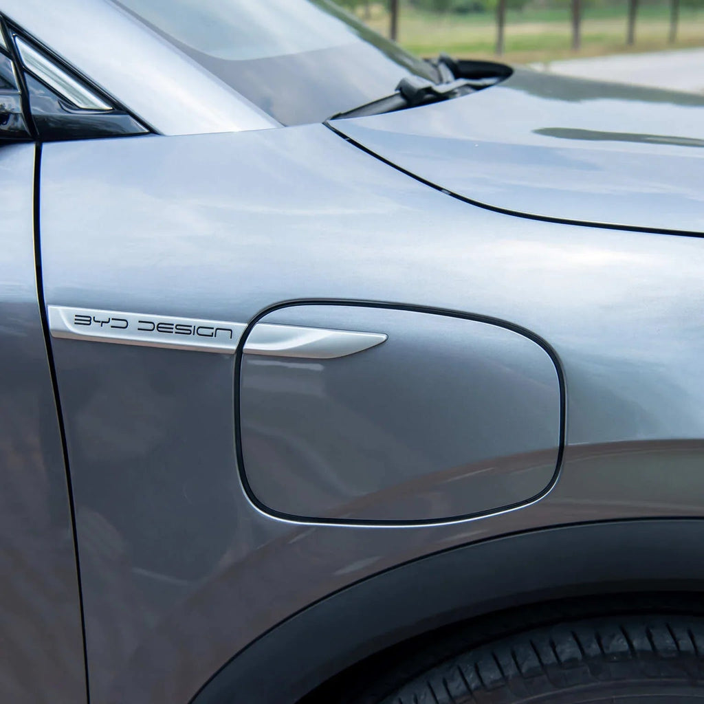 Close-up of a silver BYD Design electric vehicle charging port flap.