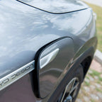 Close-up of a silver BYD Design charging port cover on a sleek grey car body.