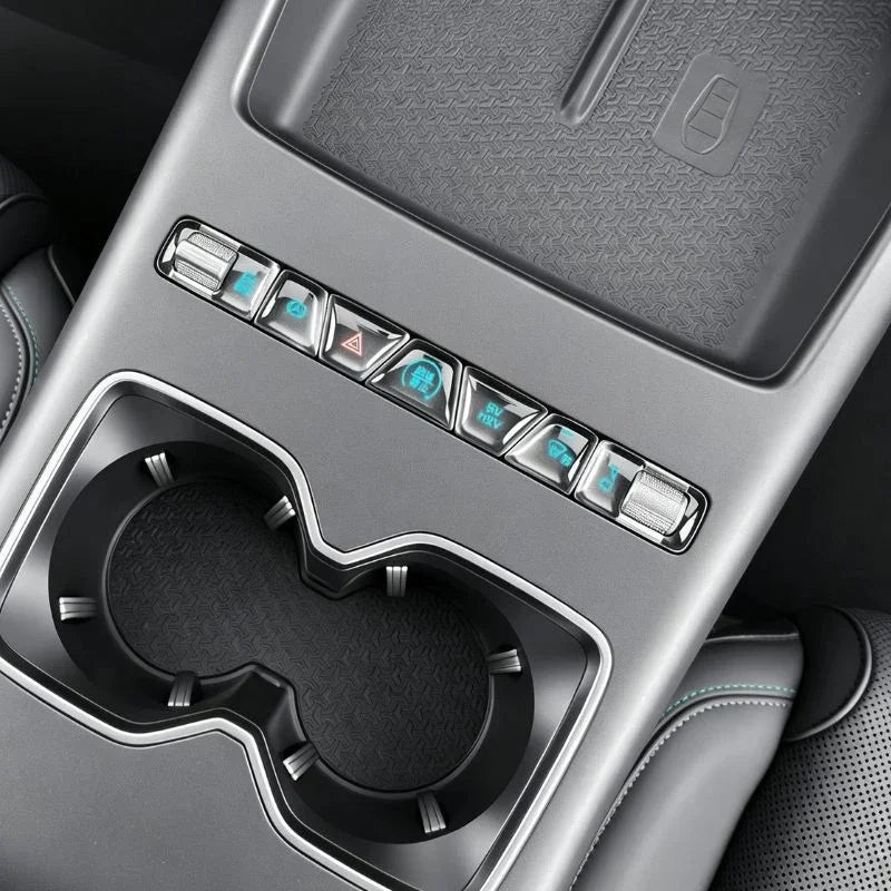 Close-up of a silver and grey car center console with metallic buttons and dual cup holders.