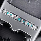 Close-up of a silver metallic center console control panel with illuminated buttons for an EV.