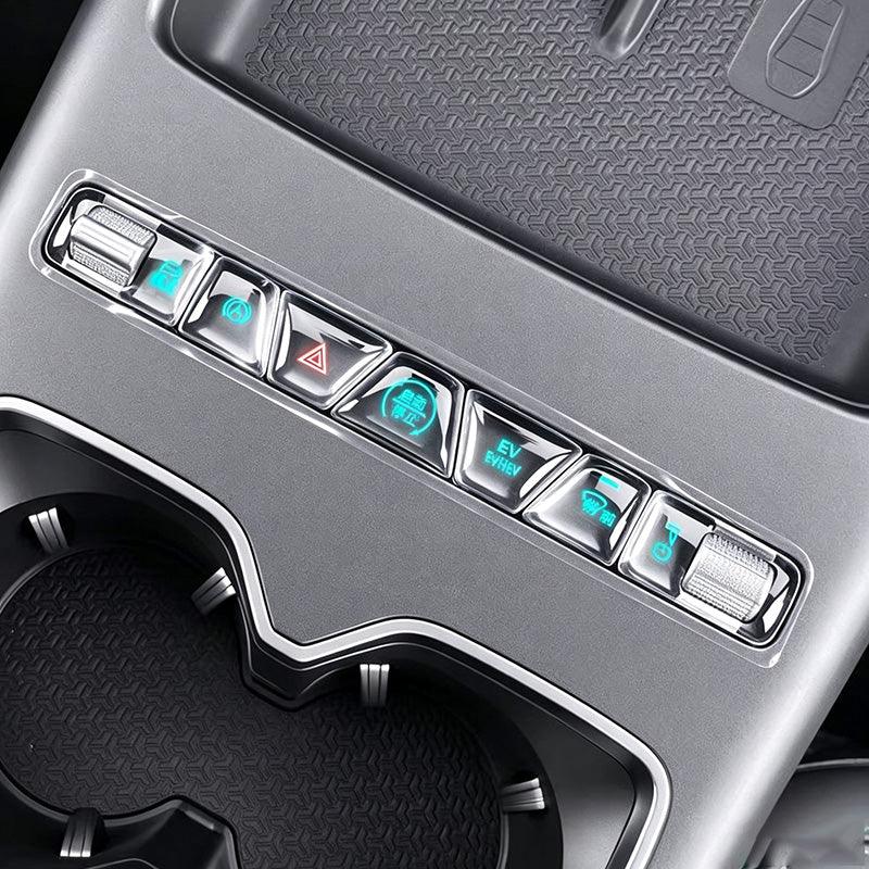 Close-up of a silver metallic center console control panel with illuminated buttons for an EV.