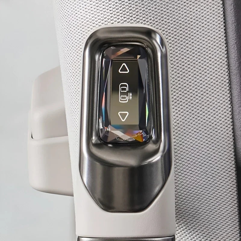 Close-up of a sleek, metallic silver window control switch with a polished finish on a textured light gray interior panel.