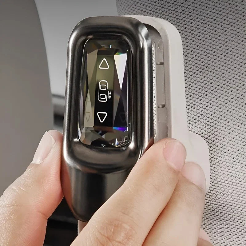 Close-up of a sleek metallic silver car key fob with a digital display showing a vehicle icon.
