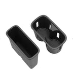 Two matte black plastic car console organizer inserts with cup holder and storage compartments