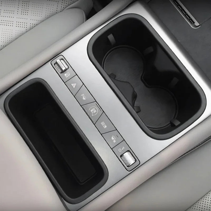 Silver metallic center console featuring dual black cup holders and integrated storage compartment.