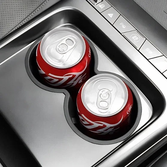 Two red soda cans placed in a black matte car cup holder accessory for BYD vehicles.