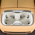 Dual beige integrated cup holders with silver trim in a tan leather car center console.