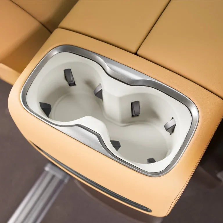Tan leather car center console with dual white plastic cup holders and silver trim.