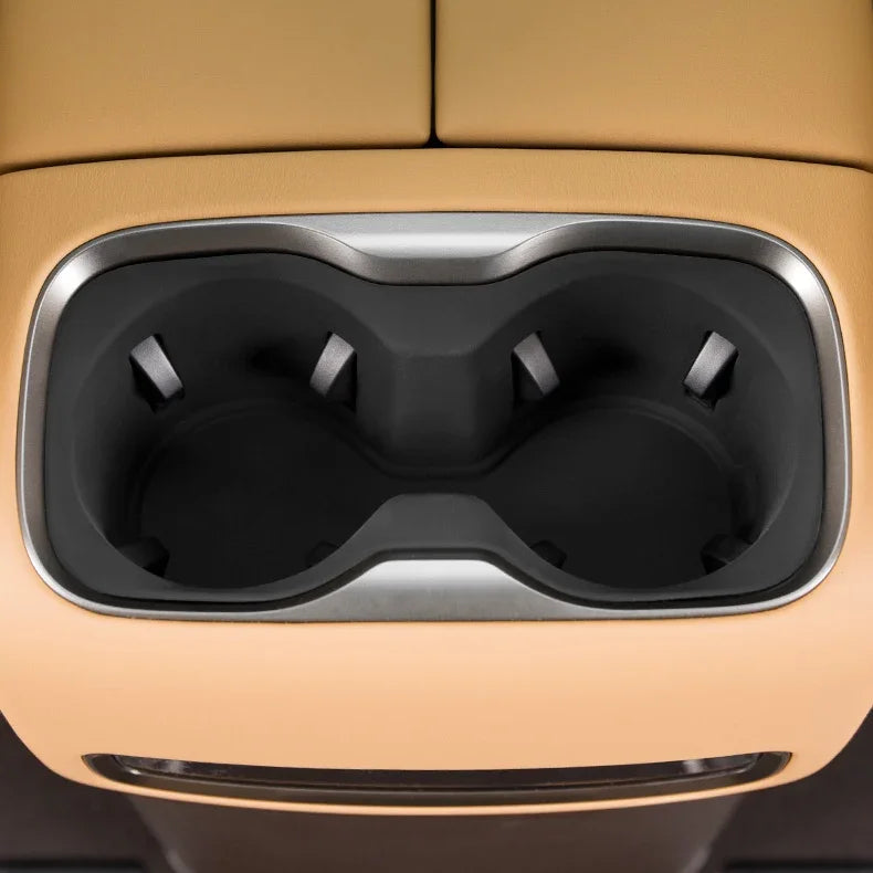 Dual black matte cup holders with silver trim integrated into tan leather car interior.