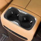 Tan leather center console with dual black matte cup holders and silver trim.
