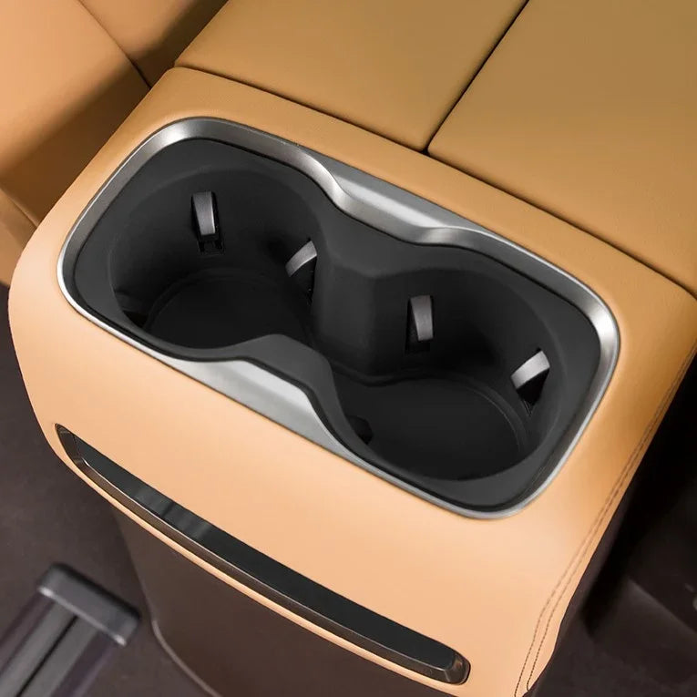 Tan leather center console with dual black matte cup holders and silver trim.