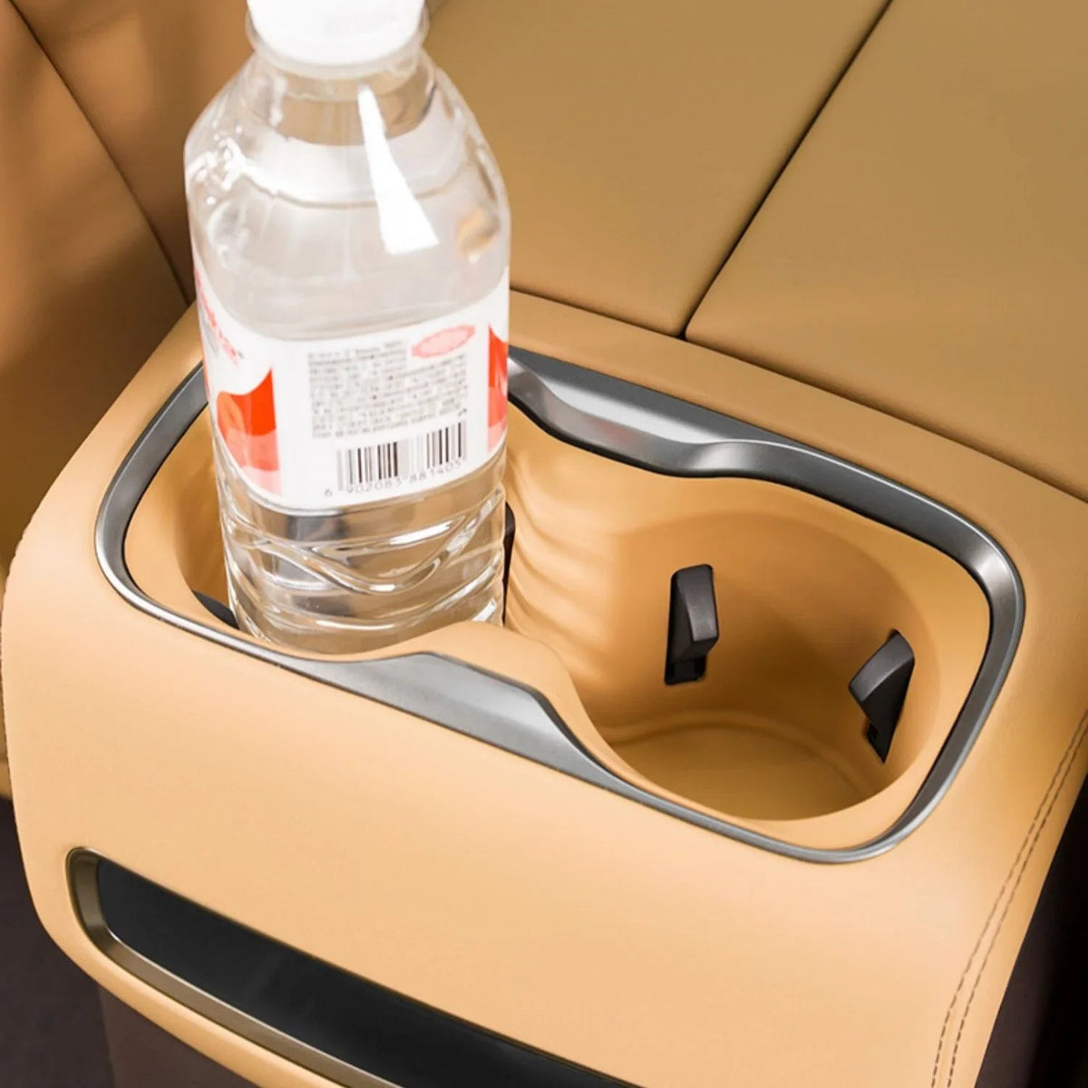 Tan leather car center console with dual integrated cup holders featuring a sleek grey trim.