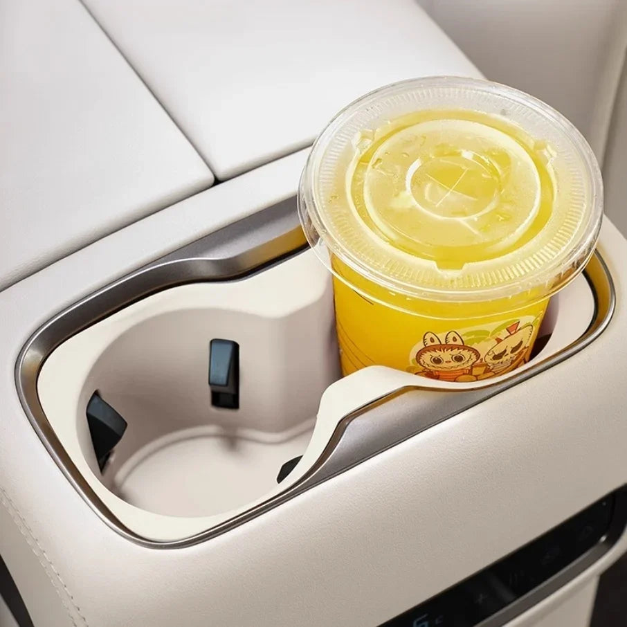 White leather car interior featuring a dual-slot center console cup holder with a yellow drink.