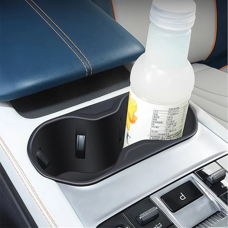 Black matte plastic car cup holder tray holding a white bottle in a BYD vehicle interior.