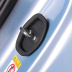 Black rubber-coated metal door handle lock mechanism on a light blue car surface.