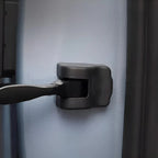 Black durable plastic latch mechanism installed on a light grey protective car interior panel.