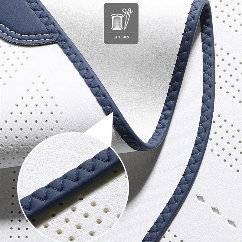 Close-up of premium white perforated leather with navy blue braided edge stitching.