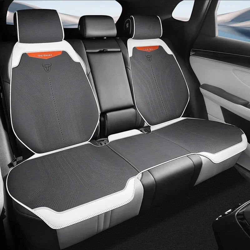 Black and white perforated leather rear car seat covers with sporty orange accent stitching.