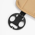 Close-up of a black plastic fastener with a black nylon strap attached to a tan perforated leather material.