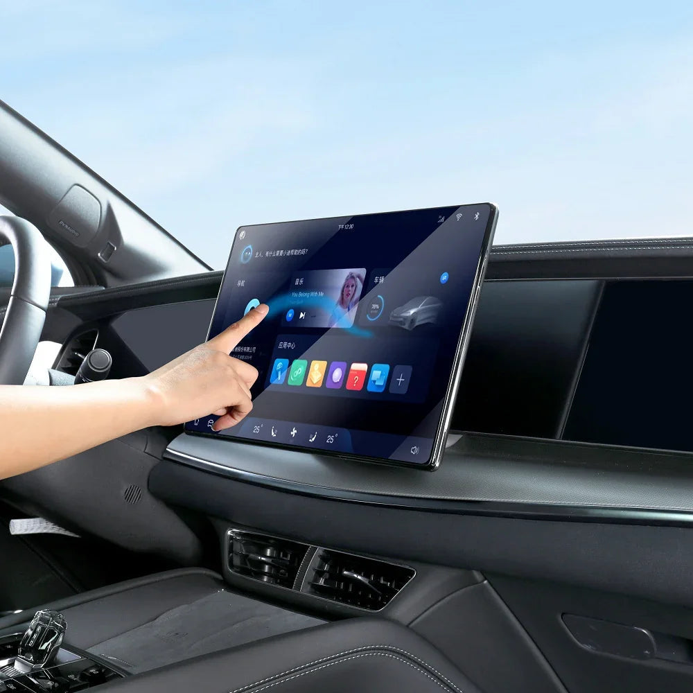 A person's hand interacting with a large, high-definition black touchscreen infotainment system in a car interior.