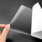 Transparent protective film being applied to a smooth black surface, showing clear material texture.