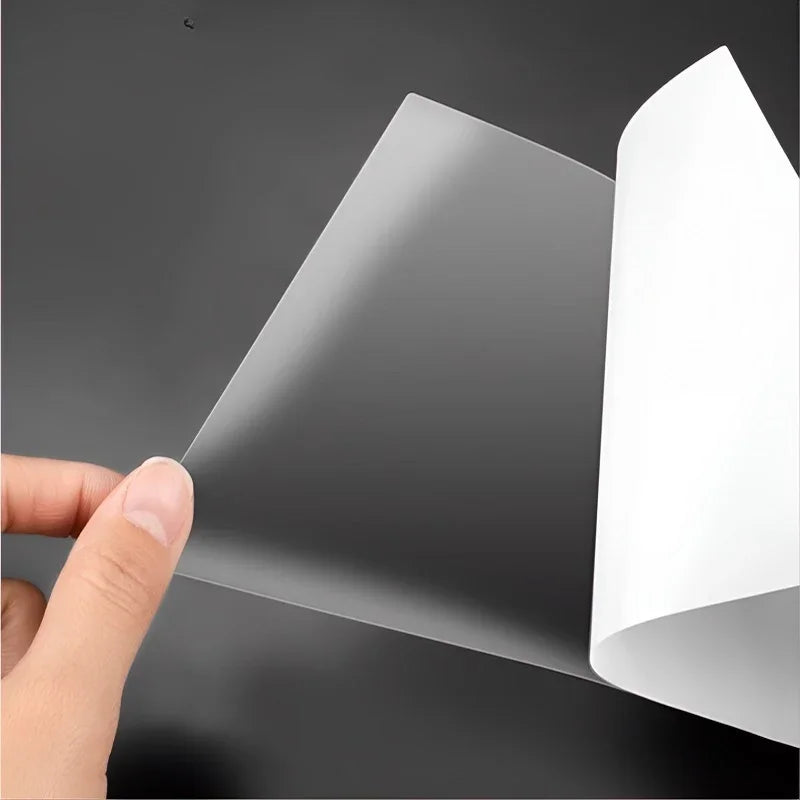 Transparent protective film being applied to a smooth black surface, showing clear material texture.