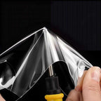 Transparent protective film being applied to a black surface with a yellow tool.