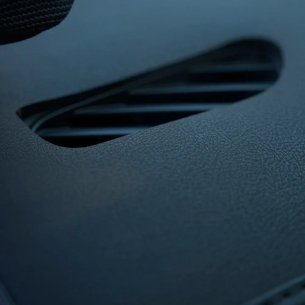Close-up of textured black leather car interior trim near a vent.
