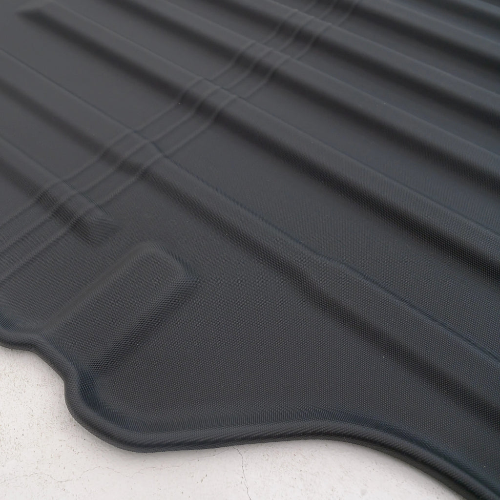 Close-up of a durable, textured black rubber car floor mat with anti-slip ridges.
