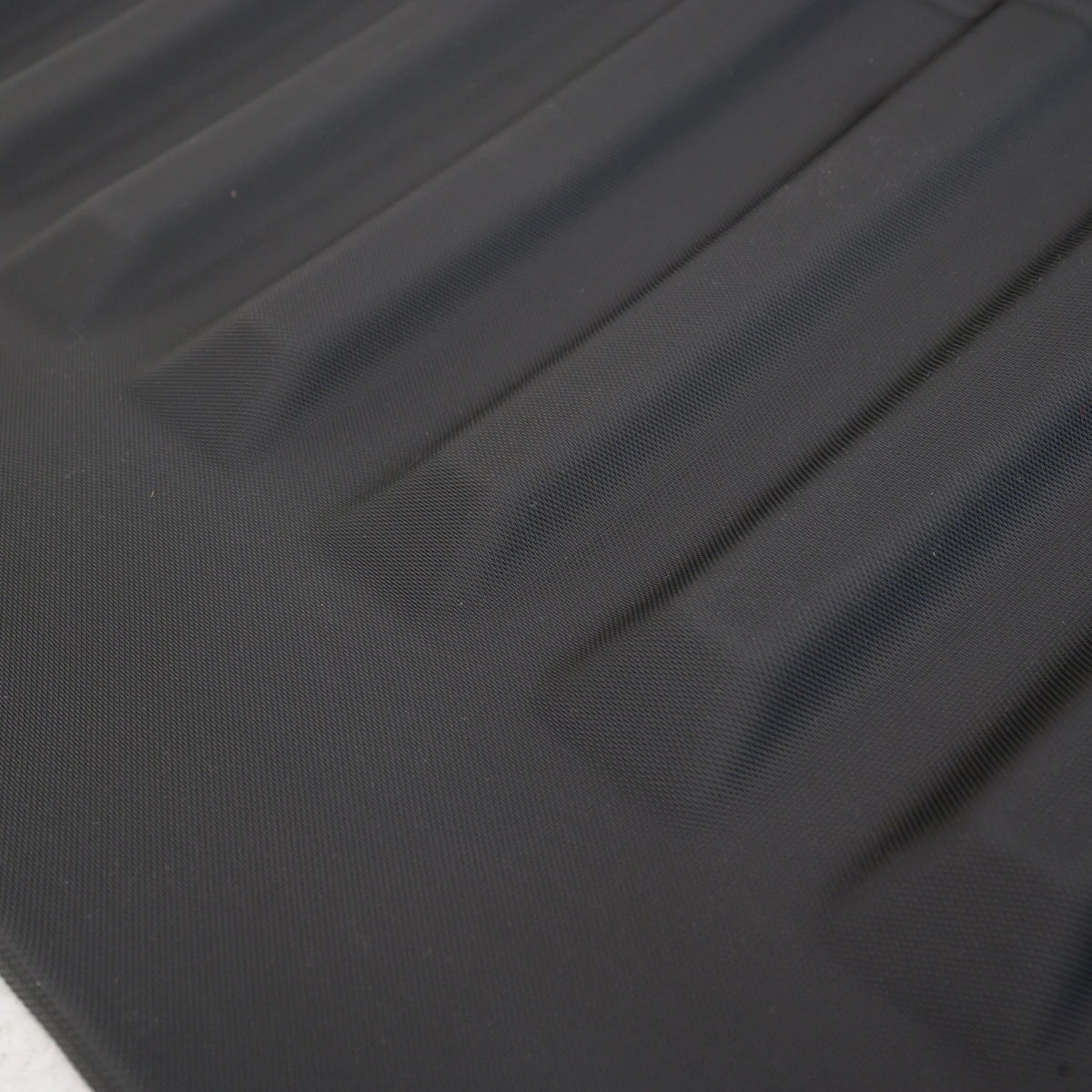 Close-up of a black textured waterproof car mat featuring durable anti-slip ridges.