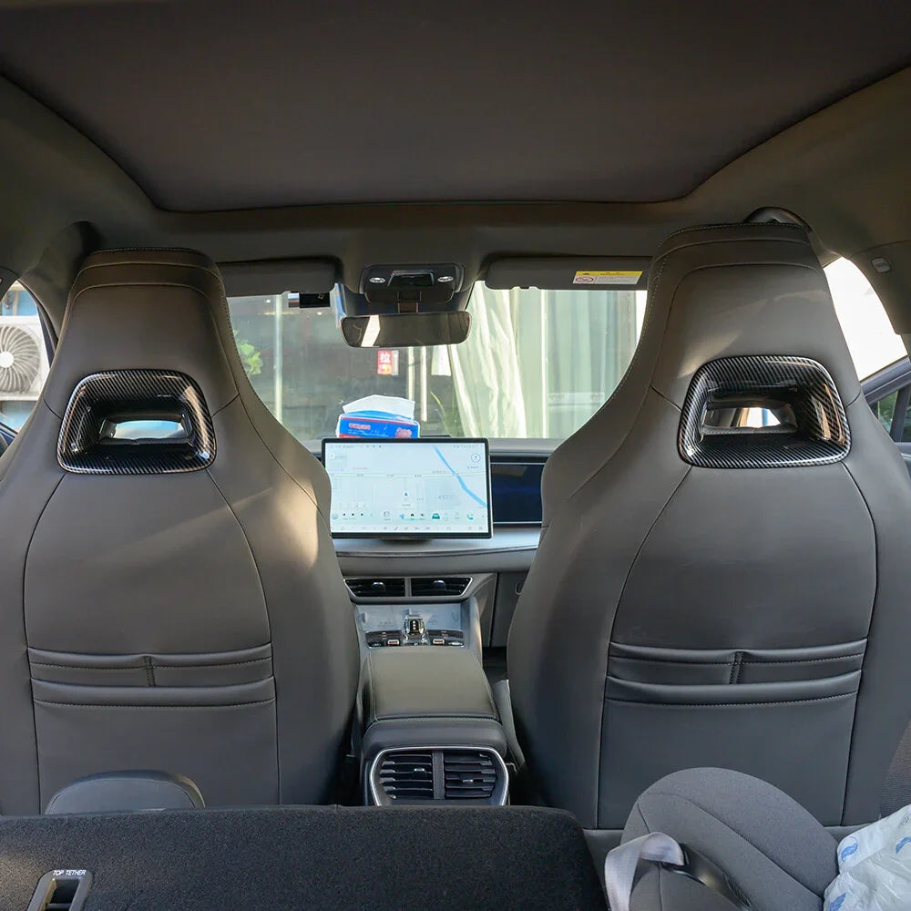 Interior view of black leather car seats featuring carbon fiber headrest accents.