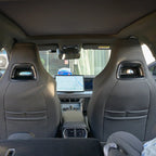 Interior view of black leather car seats featuring carbon fiber headrest accents.