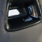 Close-up of a glossy black carbon fiber interior trim accessory for a car.