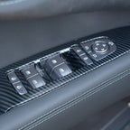 Close-up of a black carbon fiber interior trim for car door window control panel.